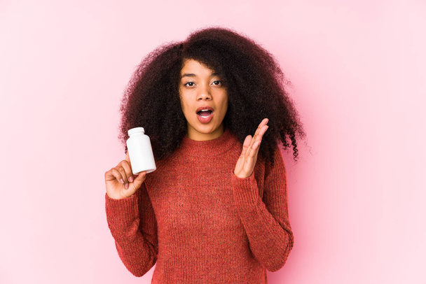 Young afro woman holding a vitamins isolated Young afro woman holding a vitaminssurprised and shocked. - Photo, image