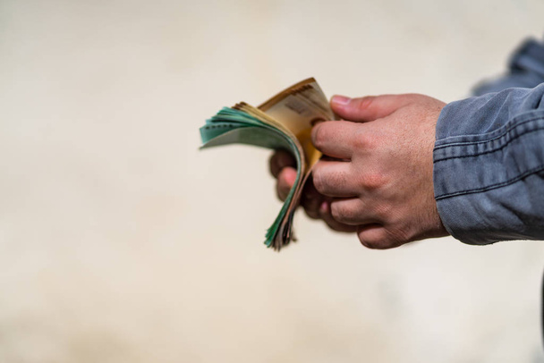 Мужчина считает деньги за взятку или чаевые. Холдинг RO bankno
 - Фото, изображение