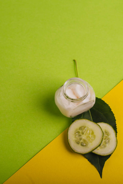 White cucumber cream on a yellow-green background. With leaves and fresh cucumber - Fotó, kép