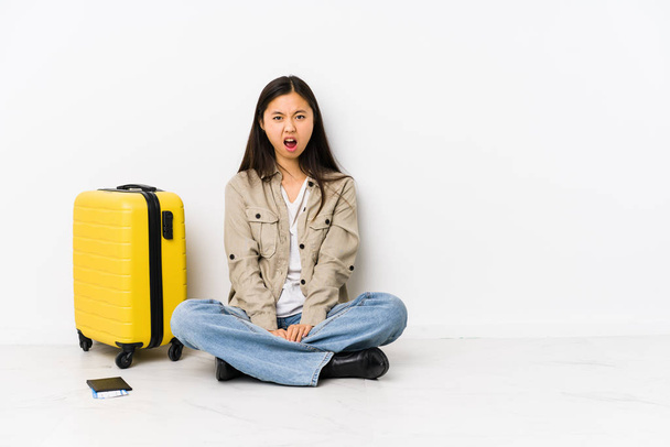 junge chinesische Reisende Frau sitzt im Besitz einer Bordkarte schreit sehr wütend und aggressiv. - Foto, Bild