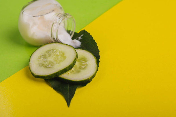 Fehér uborka krém sárga-zöld háttérrel. Levéllel és friss uborkával - Fotó, kép