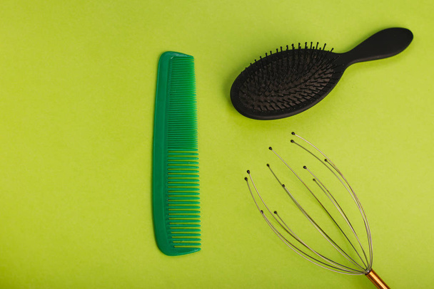 Green and black hairbrush on a green background. Chesalka, head massager. - Photo, Image