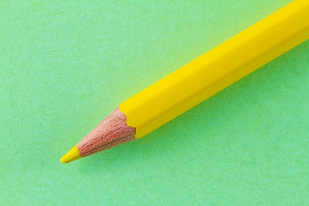 Gelber Farbstift auf grünem Farbpapier diagonal angeordnet. - Foto, Bild