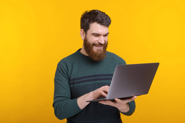 Photo of happy man surfing on internet standing over yellow background - Foto, Imagem
