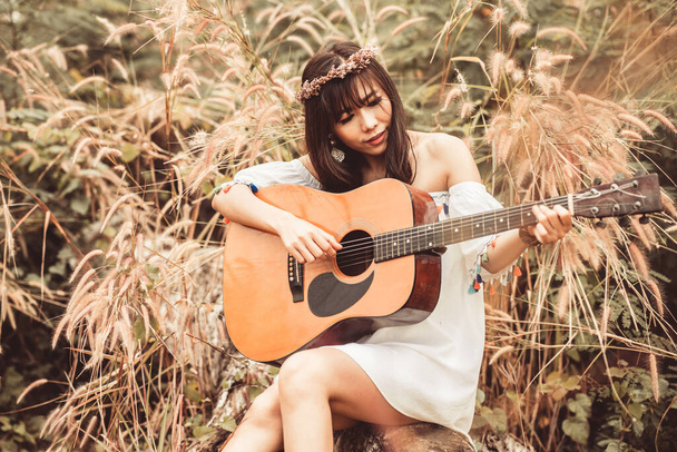 Asian woman playing guitar at beautiful field grass. Bohemian st - Fotó, kép