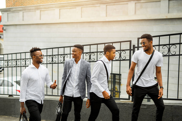 четыре молодых африканца в белых рубашках на улице летом
 - Фото, изображение