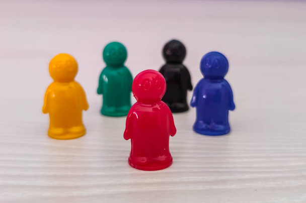 Conception  - lidership, leader in a team, diversity, game figures or pawns in a business situation. Colored chips of tabletop game in the little men form - Photo, Image