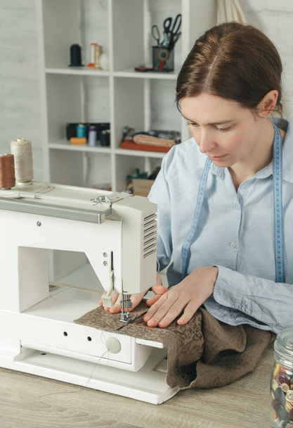 Donna che cuce sulla macchina da cucire in piccolo studio, atelier di moda, slow fashion, sartoria artigianale, abiti fatti a mano - Foto, immagini