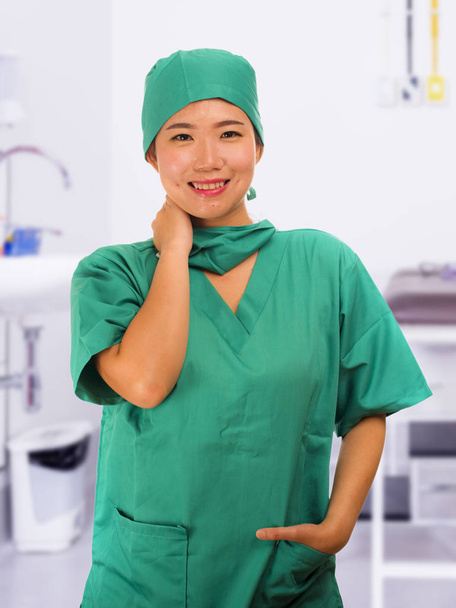 jeune belle et heureuse médecine asiatique médecin ou infirmière d'hôpital dans les gommages verts et chapeau de chirurgien souriant confiant dans le concept de soins de santé
 - Photo, image