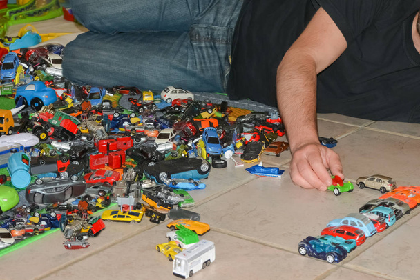 Vater spielt mit Spielzeugautos des Sohnes auf dem Boden - Foto, Bild