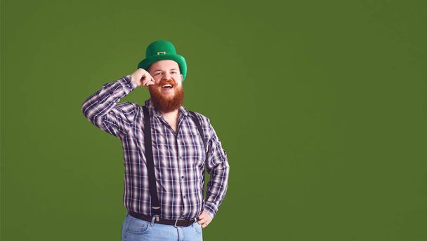 Happy St. Patricks Day. Fat man in a green hat holds his hands up glasses with beer - Valokuva, kuva