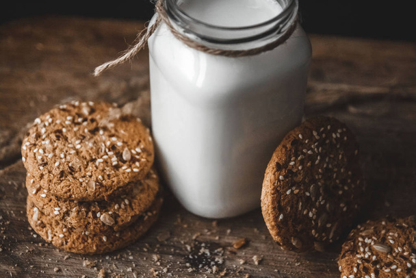 Cereal cookies with a jug of milk on a wooden background. - Foto, Imagem