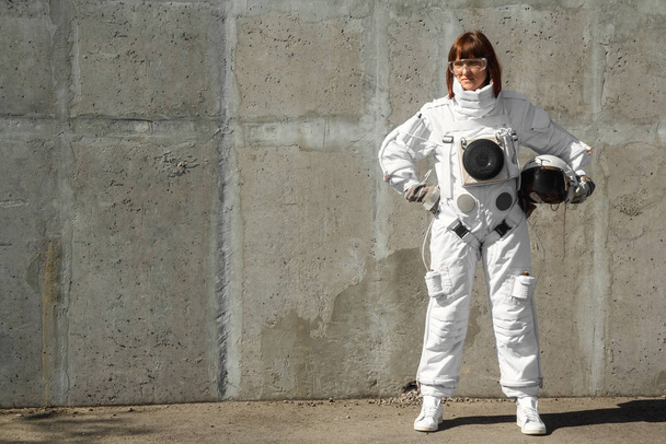 Schöne Astronautin ohne Helm auf dem Hintergrund einer grauen Wand. Fantastischer Weltraumanzug. - Foto, Bild