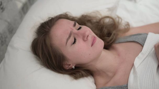 Onneton nuori nainen itkee sängyssä
 - Valokuva, kuva