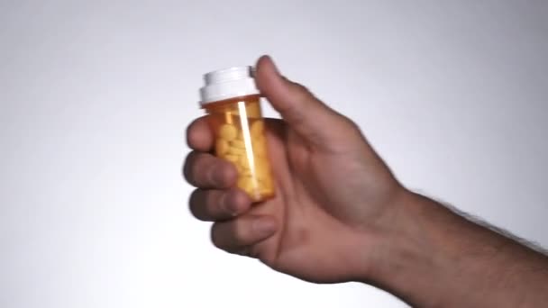 Looping shot in studio, persons arm enters frame, opens pill bottle and dumps out the medication then leaves frame. - Footage, Video