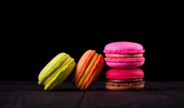 Heap of french colorful macaroons on wooden table isolated on black - Photo, Image