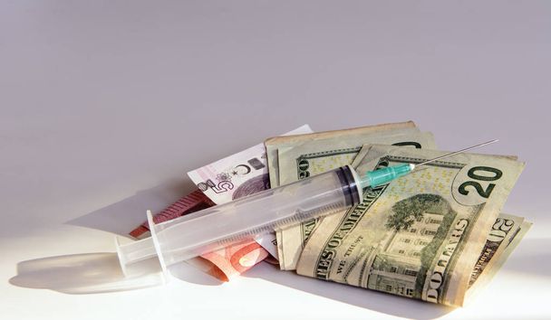 ドル、ユーロ、リラのパックの横に注射器。白地だ概念-経済危機、コロノウイルス、市場の暴落、ワクチン、危機保護 - 写真・画像