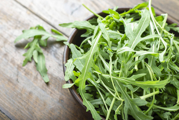 Fresh arugula leaves in a bowl on a wooden table.  - Photo, image