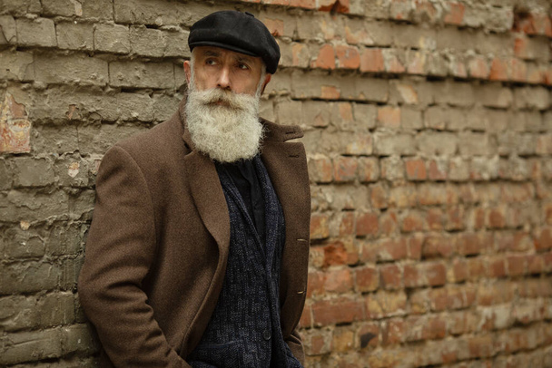 Fashionable senior man with gray hair and beard is outdoors on the street. - Foto, immagini