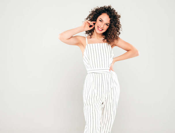Portrait of beautiful smiling model with afro curls hairstyle dressed in summer hipster clothes.Sexy carefree girl posing in studio on gray background.Trendy funny and positive woman - Foto, afbeelding