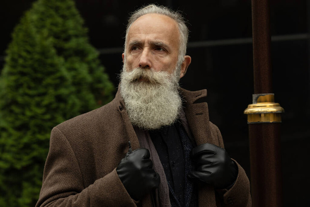 Fashionable senior man with gray hair and beard is outdoors on the street. - Φωτογραφία, εικόνα