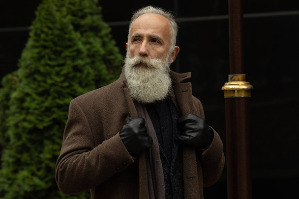 Fashionable senior man with gray hair and beard is outdoors on the street. - Valokuva, kuva