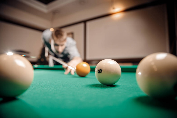 Russian billiards, man plays and beats cue on white ball - Φωτογραφία, εικόνα