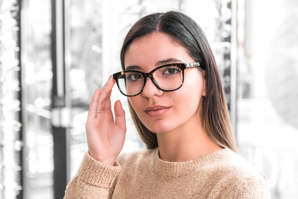 close up portrait of a beautiful woman choosing glasses. young with poor eyesight - Фото, изображение