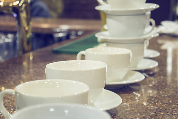 Vele rijen witte koffiebeker op tafel en cafe achtergrond. - Foto, afbeelding