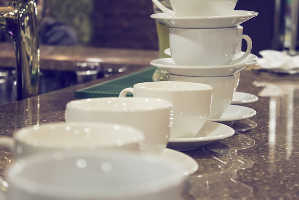Masada ve kafenin arkasında bir sürü beyaz kahve fincanı var.. - Fotoğraf, Görsel