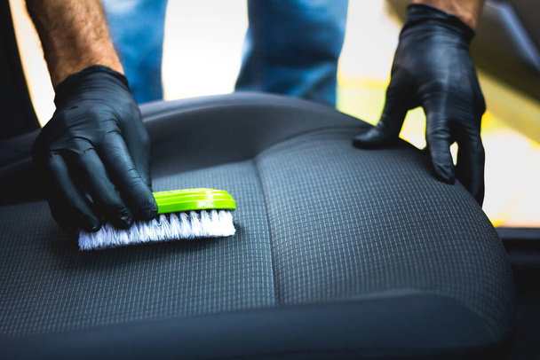De mens doet auto bekleding reinigen - Professionele chemische reiniging met zuigmethode. Hygiënische werkzaamheden en vlekverwijdering op de stoel van het voertuig - Foto, afbeelding