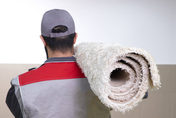 Rear view of man with a roll of carpet on shoulder - Fotoğraf, Görsel