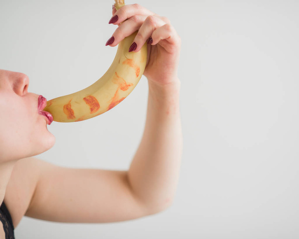 Adult European girl sexually licks and sucks a big banana. Fantasies about oral sex. Face close-up. - Foto, Bild