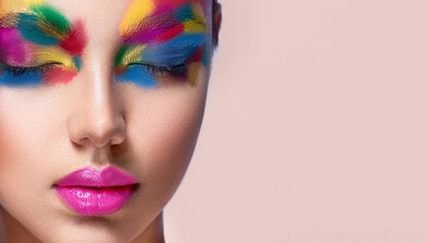Close-up detail of woman face with closed eyes covered by palette of tints. Portrait of young attractive model with face shaded in a different colors. Artistic makeup and cosmetic products. - Photo, image