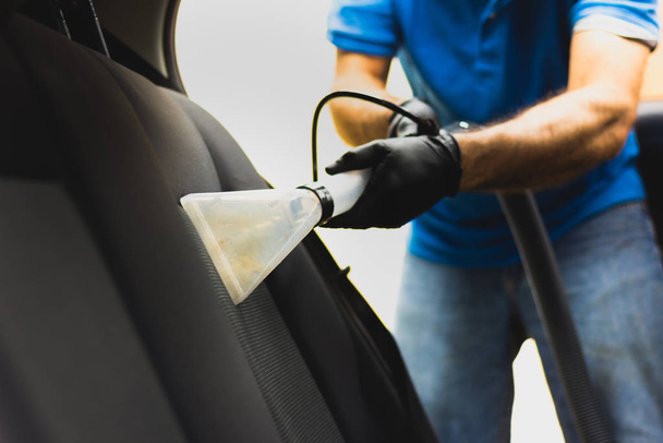 Człowiek robi czyszczenie tapicerki samochodowej - Profesjonalne czyszczenie chemiczne metodą ssania. Higieniczna praca i usuwanie plam na siedzeniu pojazdu - Zdjęcie, obraz