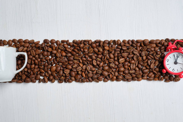 Le concept Abrakt est le moment de la préparation du café. grains de café avec une horloge rouge et une tasse blanche sur un fond en bois. Vue du dessus
. - Photo, image