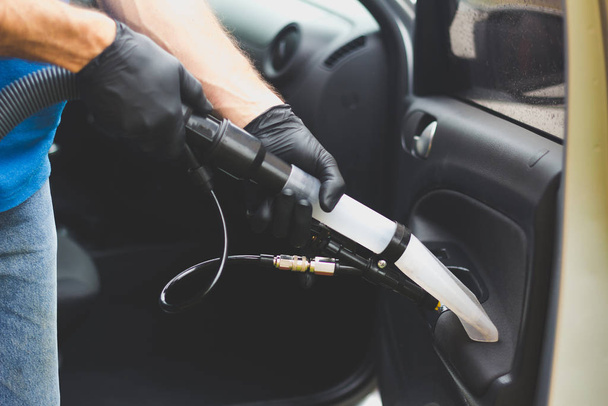De mens doet auto bekleding reinigen - Professionele chemische reiniging met zuigmethode. Hygiënische werkzaamheden en vlekverwijdering op de stoel van het voertuig - Foto, afbeelding