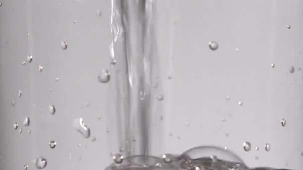 Real time close up in studion of water getting wlać w przezroczyste szkło. - Materiał filmowy, wideo