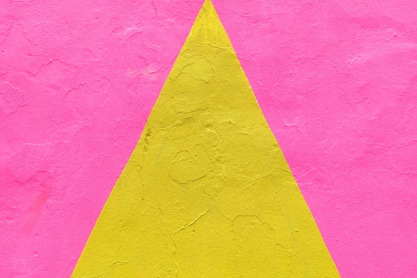 Texture abstraite en plâtre d'un triangle jaune sur fond rose
. - Photo, image
