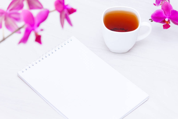 Taza de té, flores, cuaderno de papel sobre fondo blanco. Redacción, concepto freelance
. - Foto, imagen
