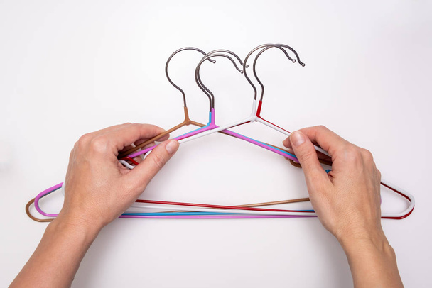 Hands holding many colorful metal wire coat, clothes hangers on white background - Foto, Bild
