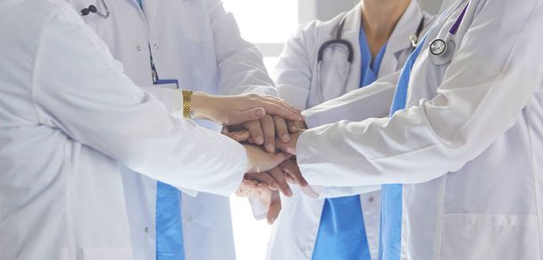 Команда медицинских работников, держащихся за руки в помещении, на виду. Концепция единства
 - Фото, изображение
