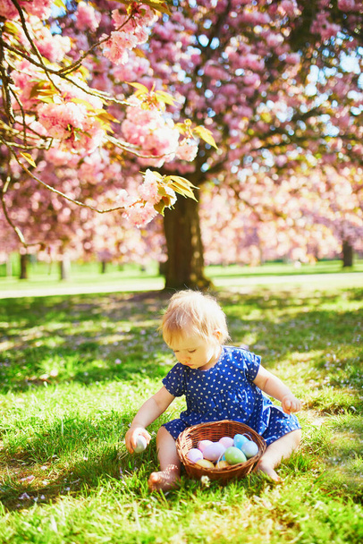 Cute one year old girl sitting on the grass and eating strawberries - Valokuva, kuva