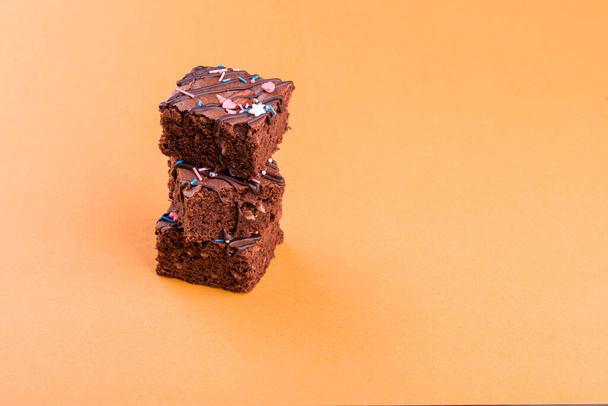 Chocolate brownie dessert with almond nut, chocolate glaze on an orange background. - Foto, imagen