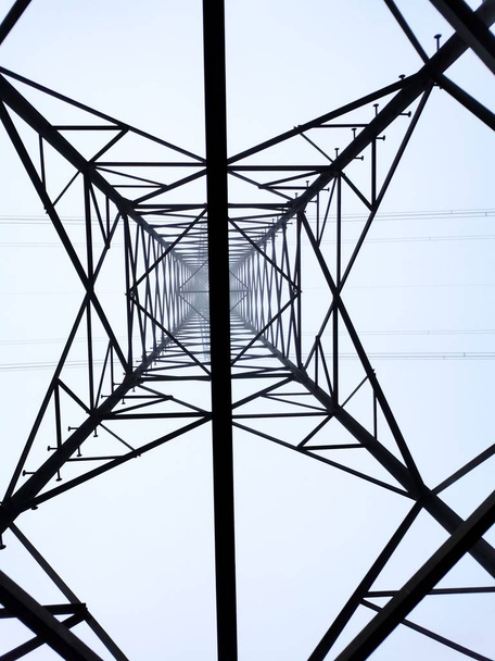 Κοιτάζοντας έναν ηλεκτρικό πυλώνα με καθαρό γαλάζιο ουρανό - Φωτογραφία, εικόνα