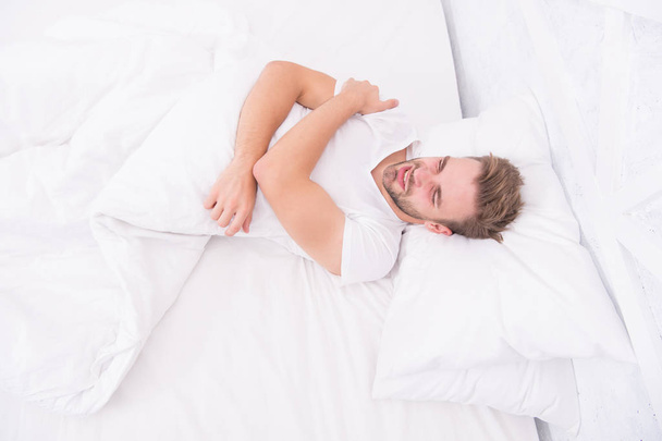 Sleep problems can lead to headaches in morning. Migraine headaches. Handsome man relaxing in bed. Snoring can increase risk headaches. Common symptom of sleep apnea. Causes of early morning headache - Photo, Image