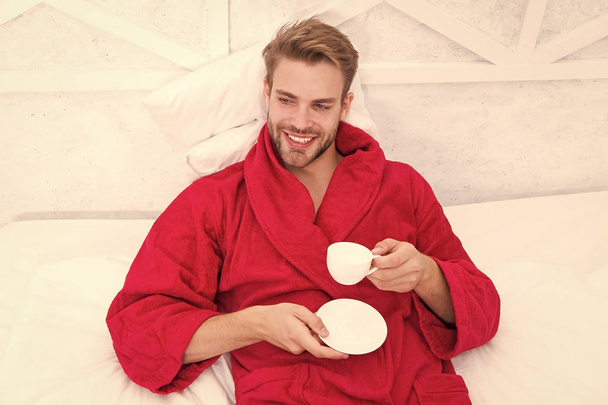 Gourmet espresso. Enjoy morning coffee. Happy morning. Handsome man drink morning coffee. Happy bearded man in bed. Good mood. Starting day with good coffee. Relaxing at home. Pleasant moments - Photo, image