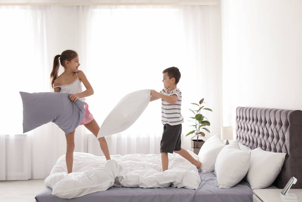 Szczęśliwe dzieci mając walki na poduszki w sypialni - Zdjęcie, obraz