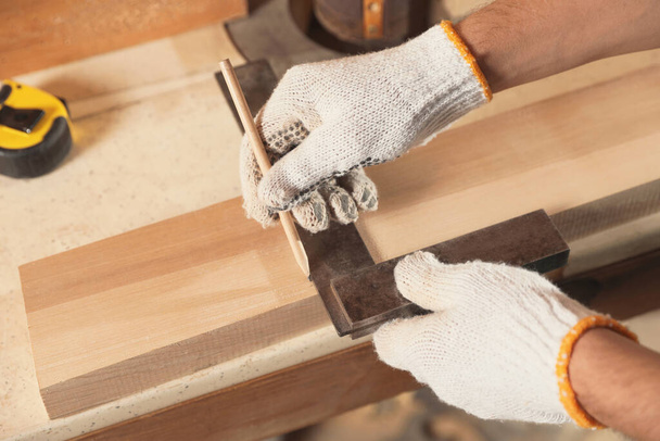 Professional carpenter working with wooden board at workbench, closeup - 写真・画像