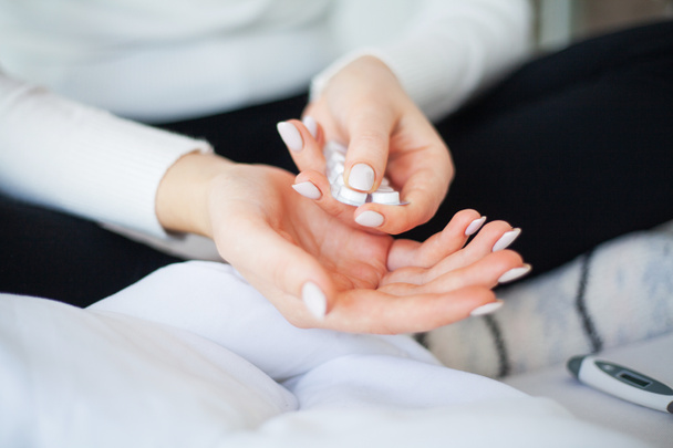 Vrouw met pillen, vrouwelijke handen op het bed met blisterverpakking van de pil - Foto, afbeelding